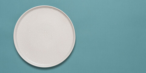 Empty beige plate on a turquoise pastel background. Top view, flat lay. Banner.