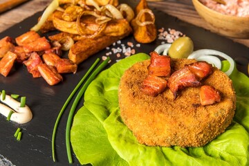 Baked camembert. Fried Camembert with chips and bacon. Fried cheese on green salad leaves.