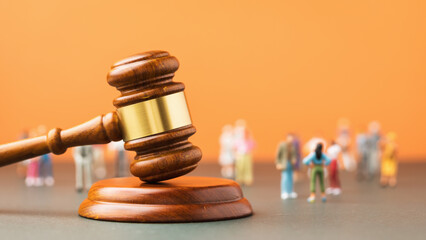 Judicial gavel and plastic toy men on a colored background, a concept on the topic of litigation in...