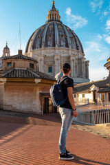 Tourist man with detailed close up view on Michelangelos Dome of St Peter Basilica in Vatican City, Rome, Lazio, Europe, EU. Architectural masterpiece of Papal Basilica of Saint Peter on sunny day