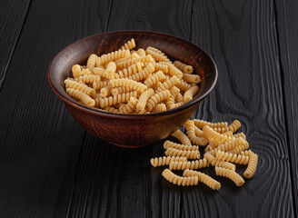 Dry fusilli pasta on black wooden table