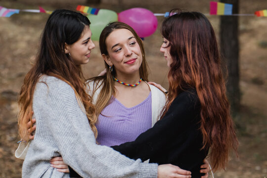 Young lesbian women in polyamory relationship. Diversity flags in background
