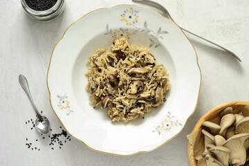 Basmati rice with brown mushrooms and sesame seeds on a gray stone background, top view