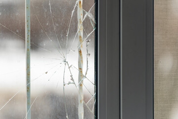 Glass broken by hooligans in a metal-plastic window, close-up