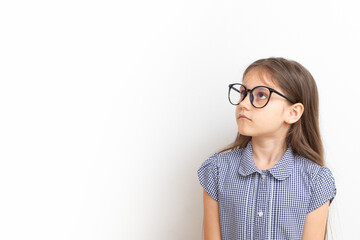 A 7-year-old girl with glasses with sad faces. Children's education, learning concept with copy...