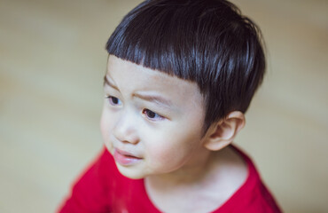 Close up of Little caucasian boy in a red T-shirt and bangs hairstyle feel upset,angry. Crop close up portrait of serious sad little Caucasian boy look away, unhappy small child kid. Emotion Concept.