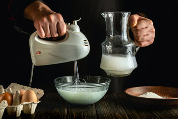 Professional chef uses a hand-held electric mixer to prepare a delicious breakfast or lunch with eggs and milk. Menu idea for a restaurant or hotel