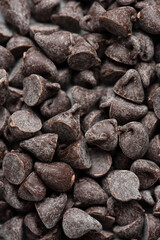 Bitter chocolate drops pattern. Closeup top view confectionery dark chocolate chips. Selective focus