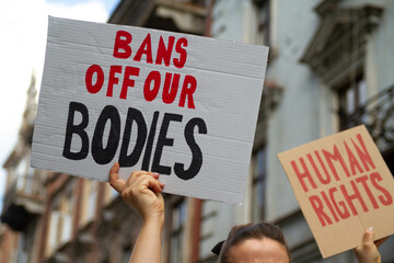 Protesters holding signs Bans Off Our Bodies and Human rights. People with placards supporting...