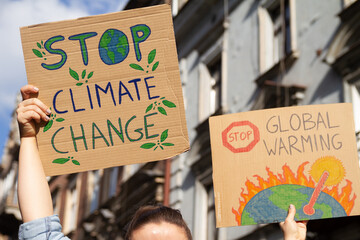 Protesters holding signs Stop Climate Change and Stop Global warming. People with placards at...