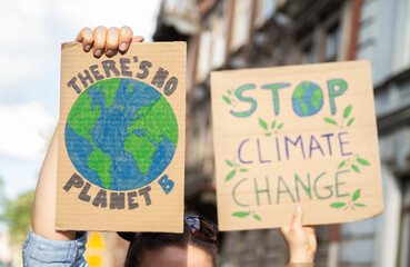 Protesters holding signs with slogans There's no planet B and Stop Climate Change. People with...