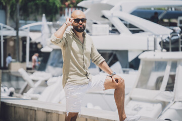 Fototapeta na wymiar Portrait of a fashion young man posing at marina and yahts background