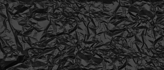 Crumpled black foil texture. Abstract dark widescreen textured background