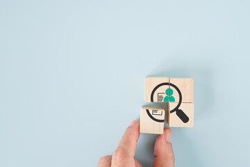 businessman's had holding wooden cube block to complete magnifying glass icon with man inside for...