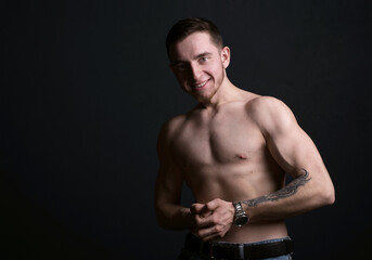 Fototapeta na wymiar Muscular model sports young man on dark background. LIGHT AND SHADOW