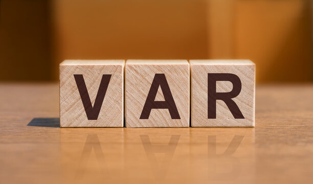 VaR - Value at Risk word on a wooden cubes on orange background.