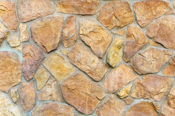 Texture. A wall of yellow stone of different shapes is fastened with cement