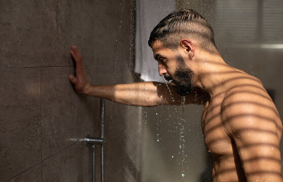 Handsome young guy taking hot shower in bathroom