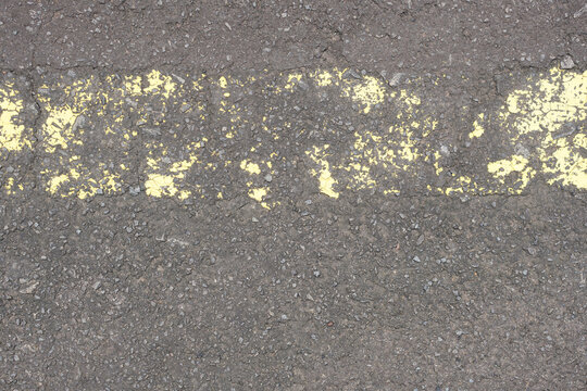 old road surface has yellow lines peeling off.