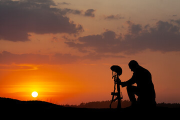 Silhouette of soldier kneeling with his head bowed on a background of sunset or sunrise. Greeting...