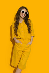 Relaxed young woman in sunglasses, yellow linen shirt and shorts - 506204705