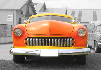Colour image of the front of orange and yellow classic vintage car. The image background...
