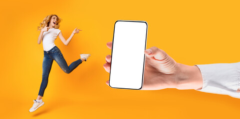 Cheerful lady jumping and pointing at empty smart phone screen