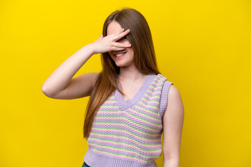 Young caucasian woman isolated on yellow background covering eyes by hands and smiling