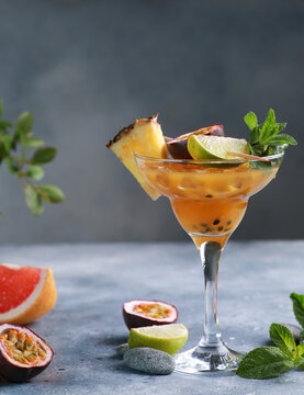 Summer. Drinks and beverage. Fruit exotic tropical cocktail with pineapple, passion fruit, grapefruit, orange, lime in a transparent glass a on a light gray background. Background image, copy space