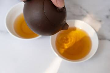 Tea from the teapot is poured into a cup. Tea ceremony concept