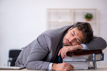Obraz premium Young male employee in oversleeping concept