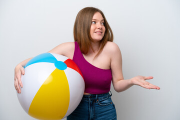 Young caucasian woman holding beach ball isolated on white background with surprise expression while looking side