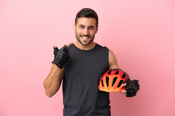 Young cyclist man isolated on pink background giving a thumbs up gesture - obrazy, fototapety, plakaty
