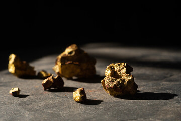 Profit, trade and exchange. Gold nuggets spilling out from a grungy old metal container, placed on a old wooden table.Shallow depth of field.selective focus.