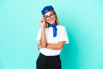 Airplane stewardess Uruguayan woman isolated on blue background with glasses and happy