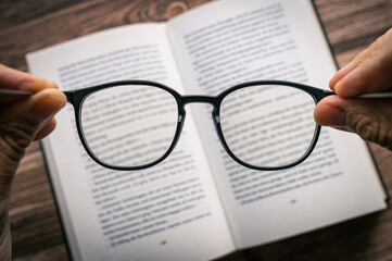 Brille wird über Buch gehalten mit Textfreiraum