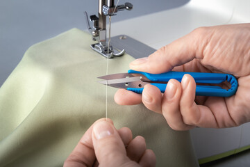 Tailor's snipper for cutting threads in the hands of a seamstress. Close-up