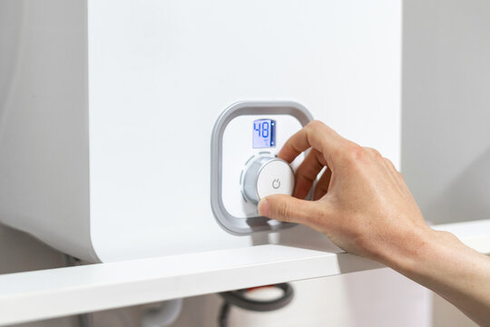 Woman turning regulate knob, adjusting temperature on boiler
