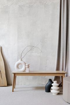 Ceramic vases with branches in room with textured walls