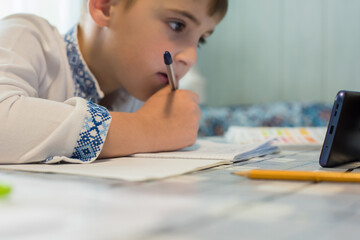 Ukrainian little boy studies online via smartphone
