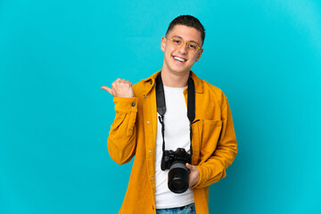 Young  caucasian photographer man isolated on blue background pointing to the side to present a...