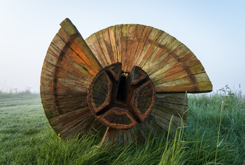 Screw of archimedes in front of a Dutch windmill on a foggy, spring day. - obrazy, fototapety, plakaty
