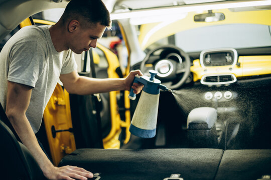 Man cleaning inside a car using spray detergent