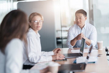 Young Asian businessman listening his colleagues on meeting in modern office. Teamwork concept