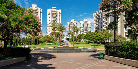 Panoramic view of a beautiful park with a water fall and fountain between high residental buildings in Ramat-Gan town , Israel