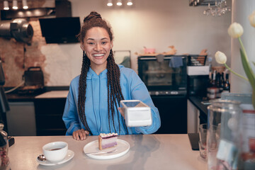 Happy young female bartender handing payment terminal for coffee and cheesecake in cafe. Portrait.