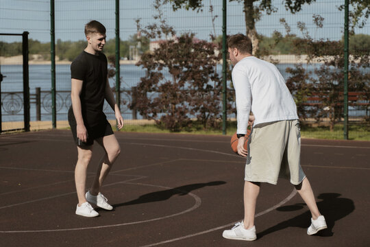 two guys play basketball outdoors on the court