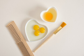 egg-based face, hair and body mask, DIY natural cosmetics concept,comb, brush and egg in a heart-shaped bowl