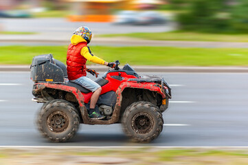 quad bike at speed rides on the road in the city with motion blur effect. Selective focus. The concept of freedom, adventure and travel.