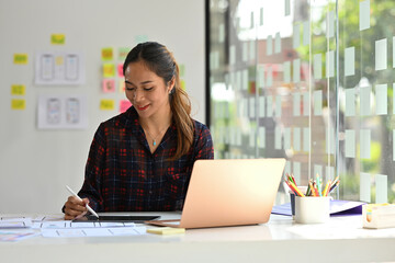 Young Asian designer working with laptop computer in creative office, Developing a New app design...